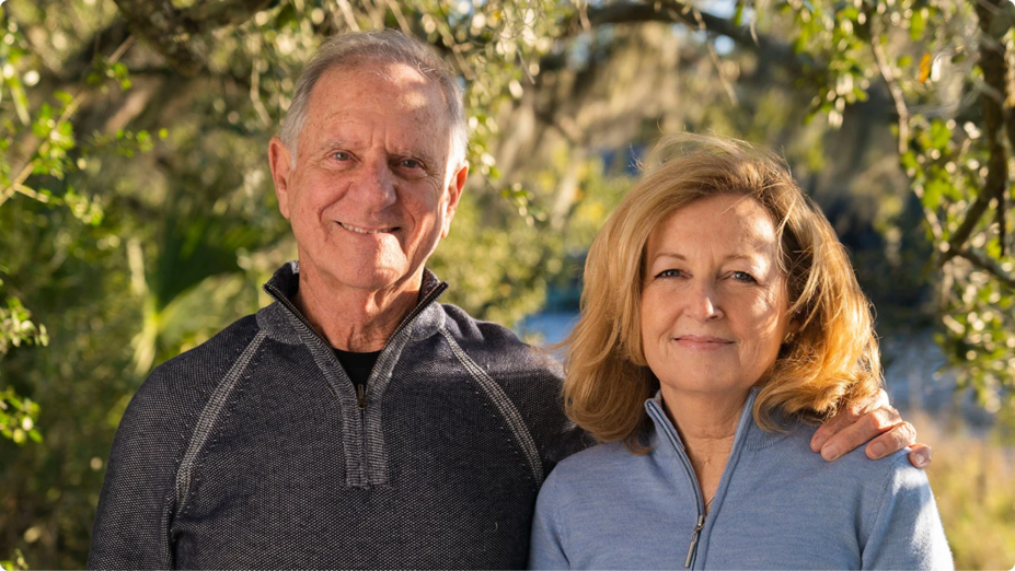 Image shows Trish, an actual KYMRIAH® patient standing in the forest along with a senior citizen man who is taking his shoulder.